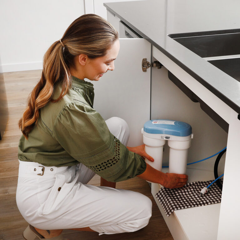 woman holding puratap filter unit for under sink water filtration